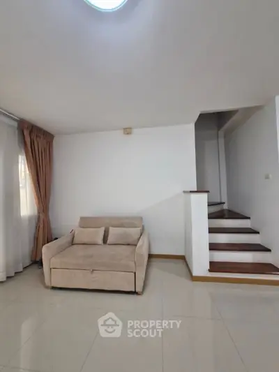 Spacious living room with modern sofa and elegant staircase