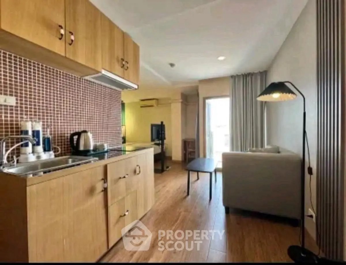 Cozy open-layout living room with kitchenette, modern decor, and natural light.