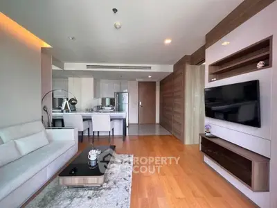 Modern living room with open kitchen, sleek furniture, and wooden flooring in a stylish apartment.