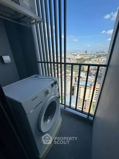 High-rise apartment balcony with washing machine and stunning city view.