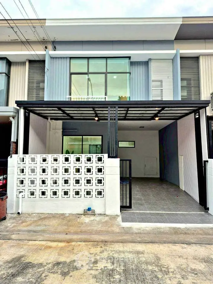 Modern two-story townhouse with sleek facade and spacious carport in urban setting.