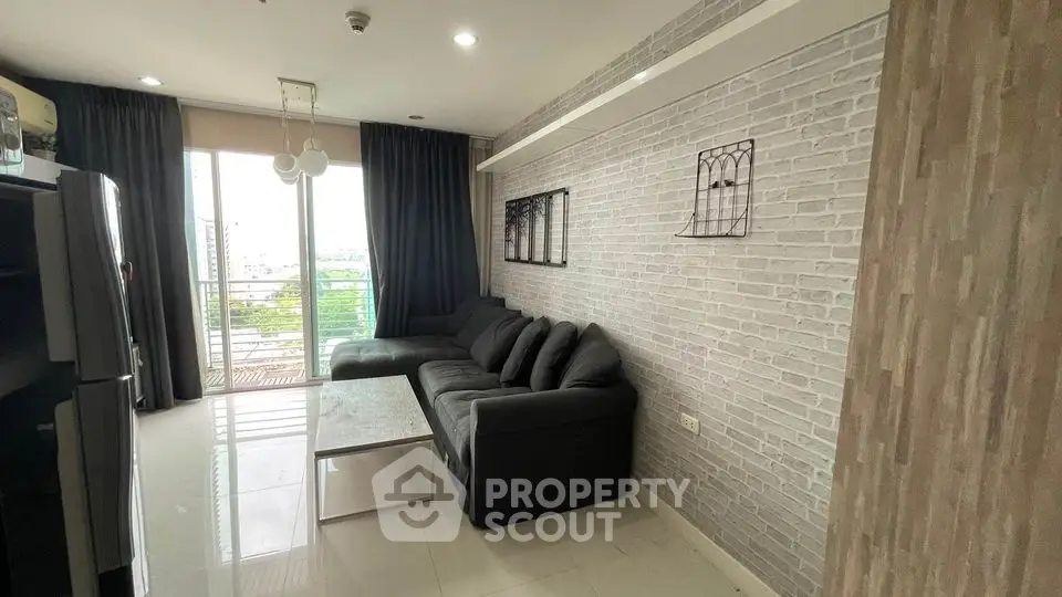 Modern living room with sleek gray sofa and large windows offering natural light and city view.