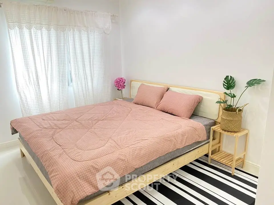 Cozy bedroom with stylish decor and natural light, featuring a comfortable bed and modern accents.