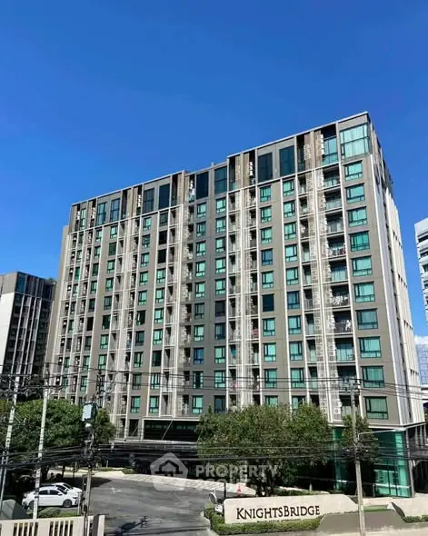 Modern high-rise building with sleek design and large windows under clear blue sky.