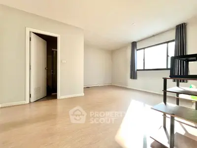 Spacious empty room with large window and wooden flooring, ideal for customization.