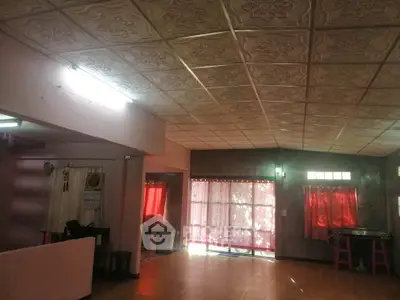 Spacious living area with decorative ceiling tiles and natural light