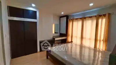 Spacious bedroom with large window and modern furniture, perfect for comfort and relaxation.