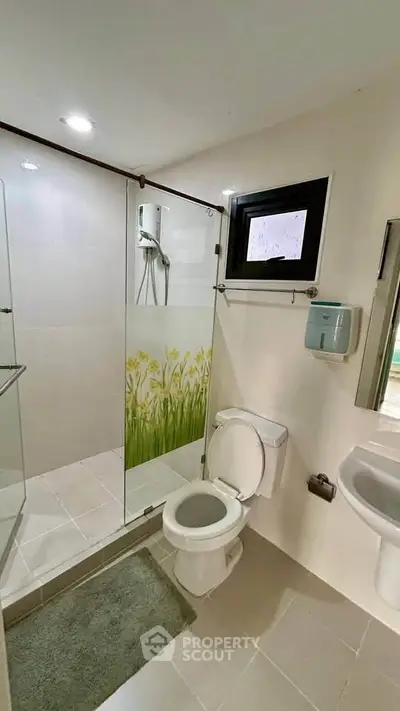 Modern bathroom with glass shower and sleek fixtures in contemporary home.