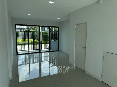 Spacious modern living room with glossy tiled floors and large windows overlooking garden.