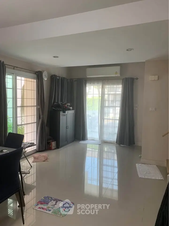 Spacious living room with large windows and modern decor, perfect for family gatherings.