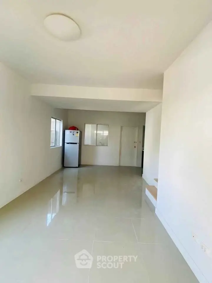 Spacious unfurnished room with glossy tile flooring and natural light