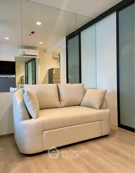 Modern living room with beige sofa and mirrored wall, perfect for cozy relaxation.