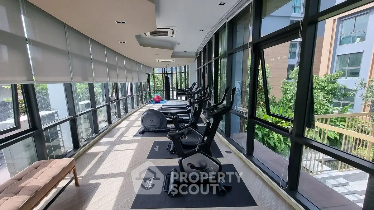 Modern gym with large windows and exercise equipment in a luxury apartment building.