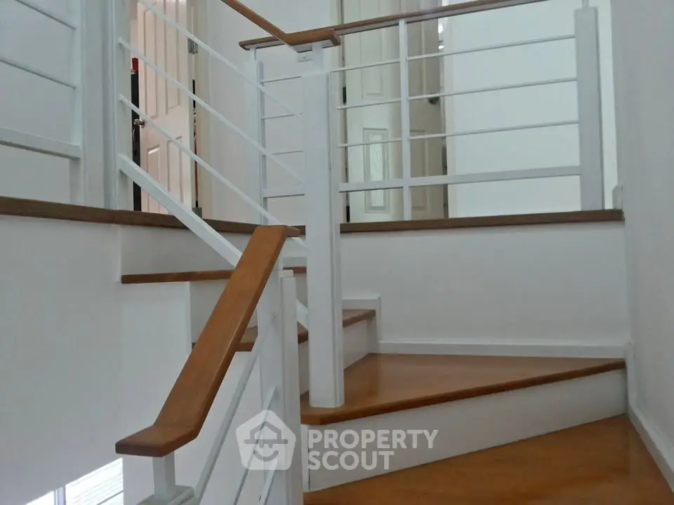 Modern staircase with wooden steps and white railings in a stylish home interior.