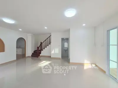 Spacious modern living room with glossy tile flooring and staircase