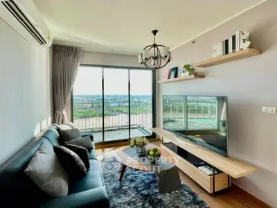 Modern living room with large windows and balcony offering stunning city views.