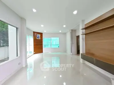Spacious modern living room with large windows and built-in wooden shelves.