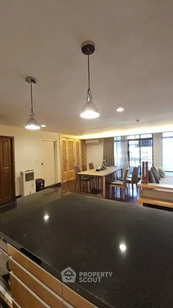 Spacious open-plan living and dining area with modern lighting and large windows.