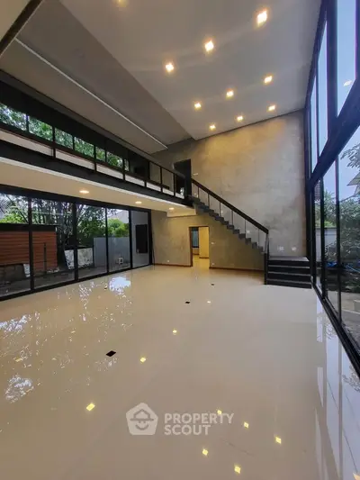 Spacious modern living room with high ceilings and large windows offering natural light and garden view.