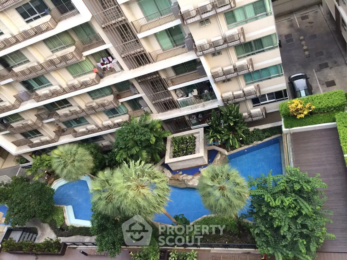 Aerial view of modern apartment building with lush pool and greenery