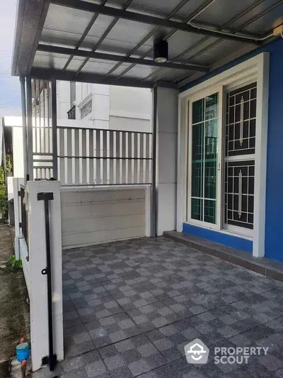 Modern home entrance with stylish blue facade and tiled porch