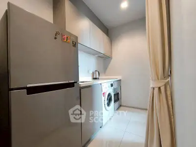 Modern kitchen with sleek appliances and washing machine in compact layout.