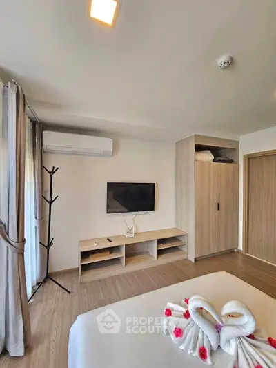 Modern bedroom with stylish decor, featuring a wall-mounted TV, air conditioning, and elegant wooden furniture.