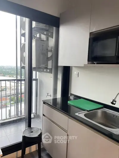 Modern kitchen with balcony view and sleek appliances in urban apartment.