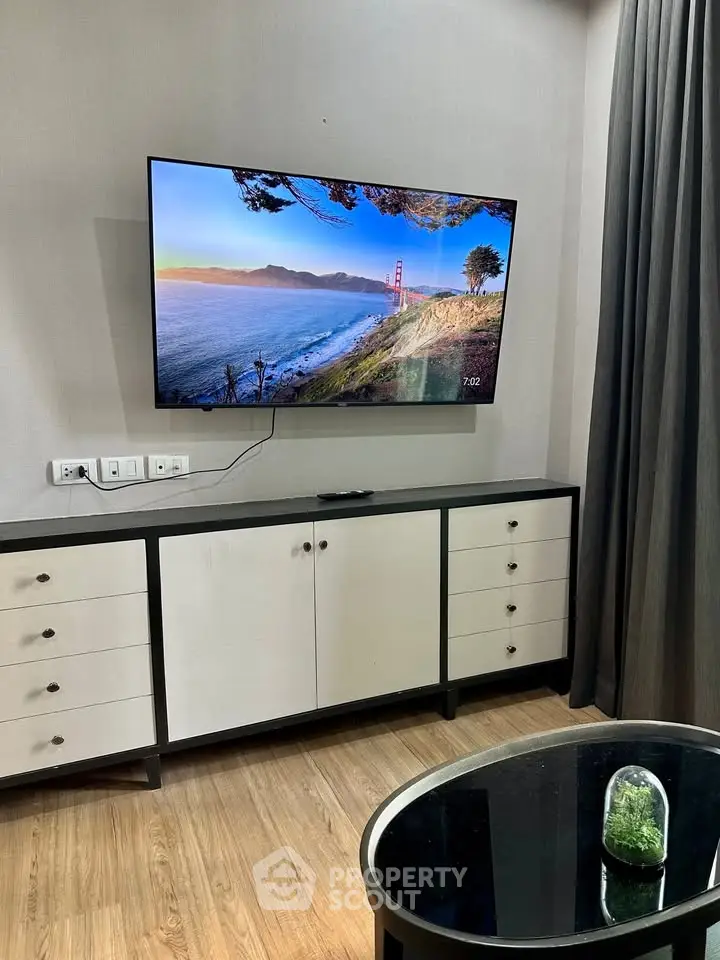 Modern living room with wall-mounted TV and stylish cabinet, featuring elegant decor and wooden flooring.