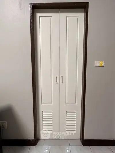 Compact storage closet with white folding doors in modern interior.