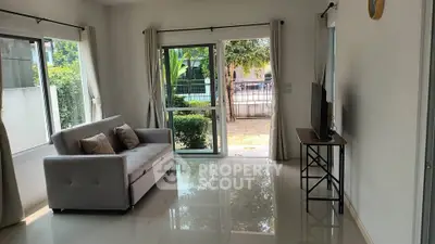 Bright living room with modern sofa and garden view through large windows.