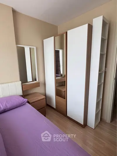 Cozy bedroom with modern wardrobe and purple bedding in a stylish apartment.