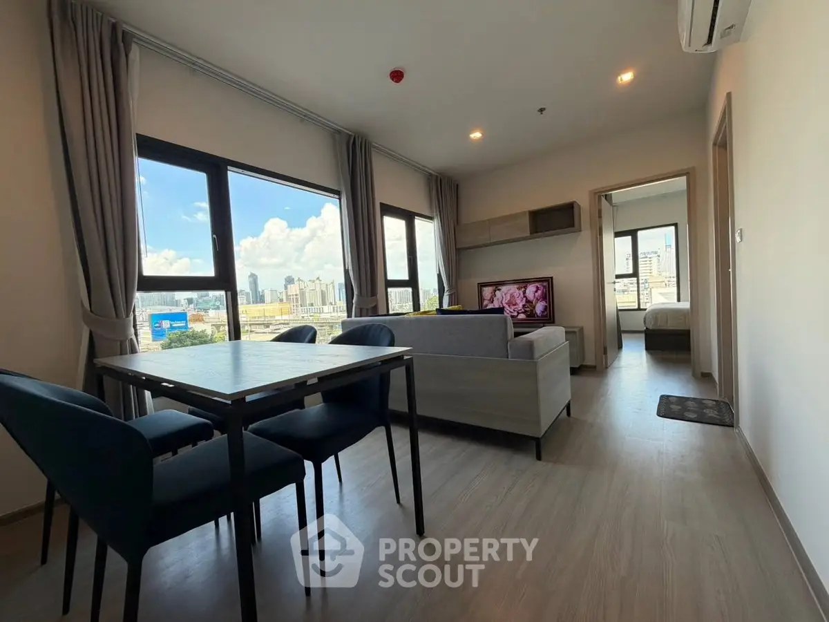 Modern living room with city view, open layout, and stylish furniture in a high-rise apartment.