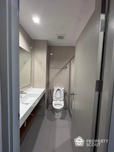 Modern bathroom with sleek design and spacious layout, featuring a large mirror and contemporary fixtures.