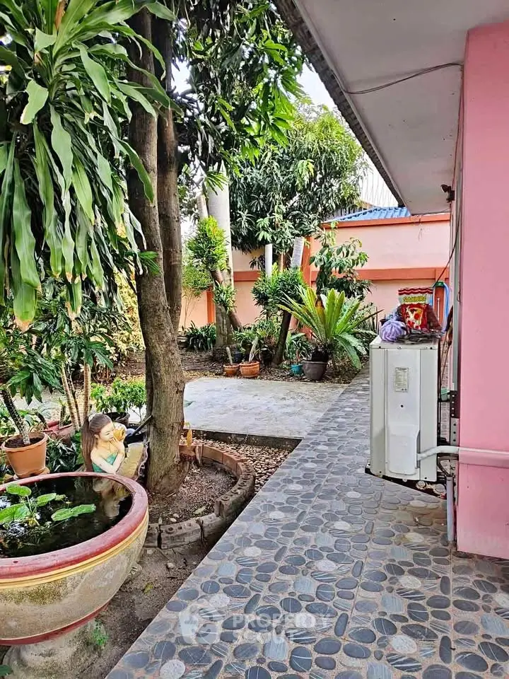 Charming garden area with lush greenery and paved walkway in residential property.