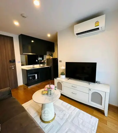 Modern living room with sleek kitchen, air conditioning, and stylish decor in a cozy apartment.