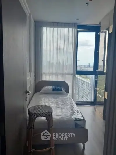 Cozy bedroom with single bed and large window offering city view