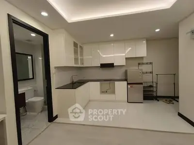 Modern kitchen with sleek cabinets and adjacent bathroom in a compact apartment layout.