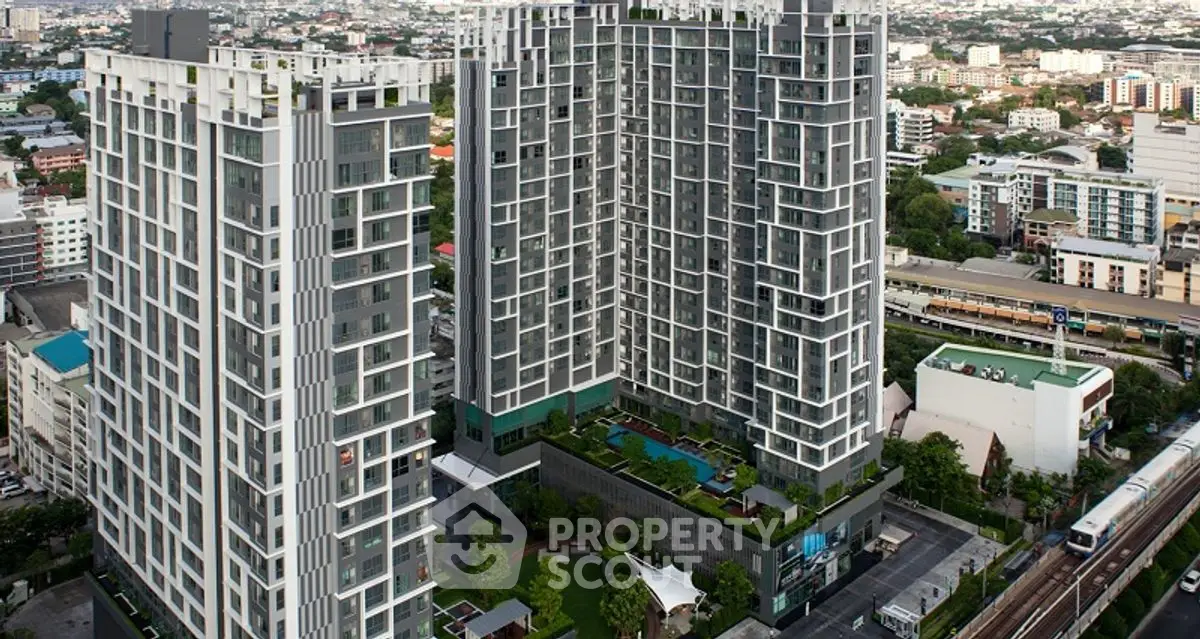 Modern high-rise residential buildings with cityscape view and lush greenery.