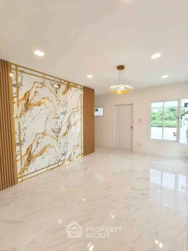 Luxurious living room with marble accent wall and modern lighting in a bright, spacious interior.