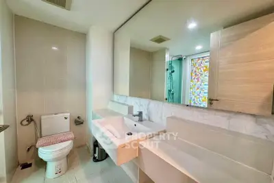 Modern bathroom with sleek fixtures and a large mirror, featuring a stylish shower area with colorful glass accents.
