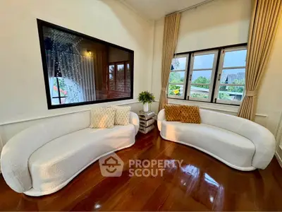 Elegant living room with stylish white sofas and large windows offering a scenic view, perfect for relaxation.