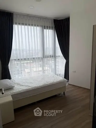 Modern bedroom with large windows and city view, featuring elegant curtains and minimalist design.