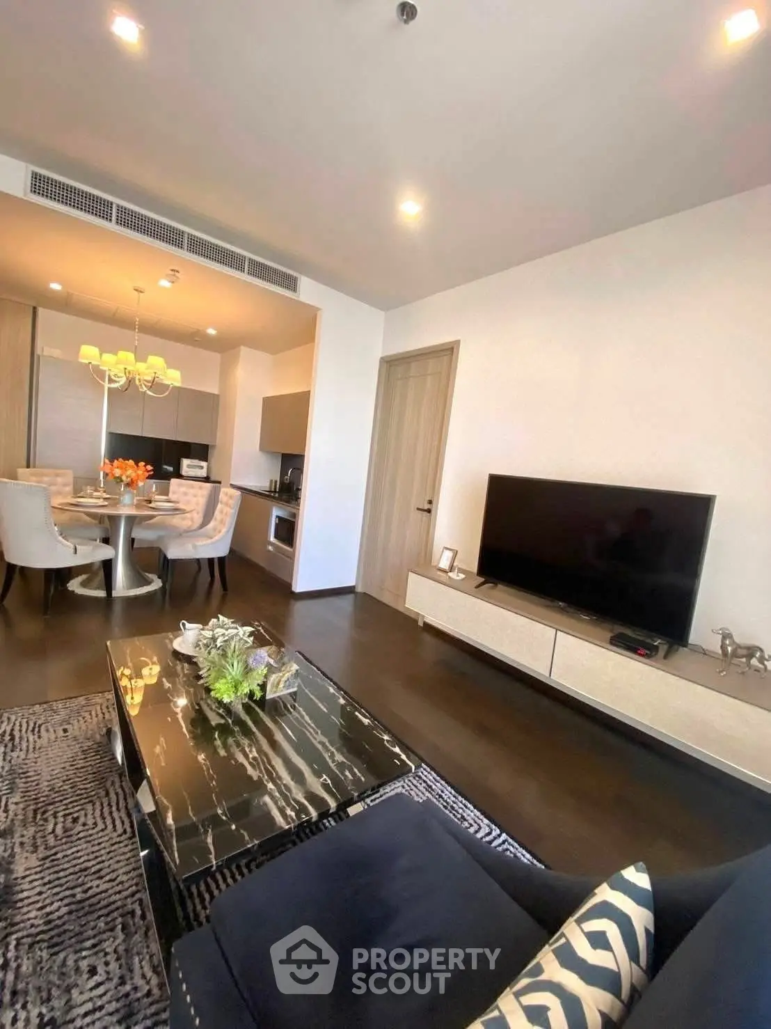 Modern living room with open kitchen, stylish decor, and dining area in a contemporary apartment.