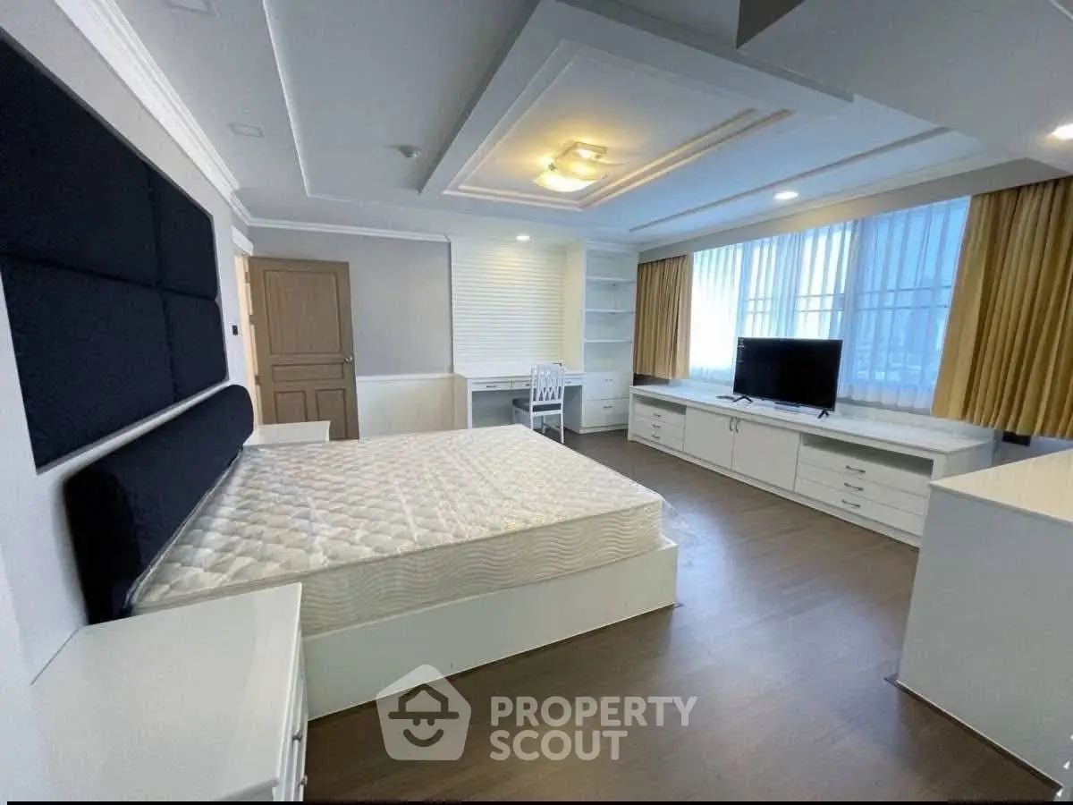 Spacious modern bedroom with large windows and elegant furnishings.