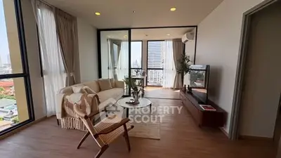Spacious modern living room with large windows and city view, featuring stylish furniture and decor.