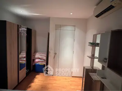 Modern bedroom with wooden flooring, sleek wardrobe, and air conditioning unit.