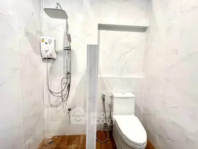 Modern bathroom with sleek shower and toilet in a stylish tiled setting.