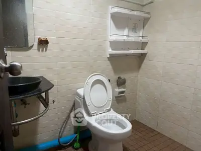 Functional bathroom with modern fixtures and tiled walls, featuring a toilet and sink.