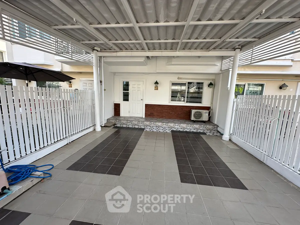 Charming covered entrance with tiled flooring and white picket fence, perfect for welcoming guests.